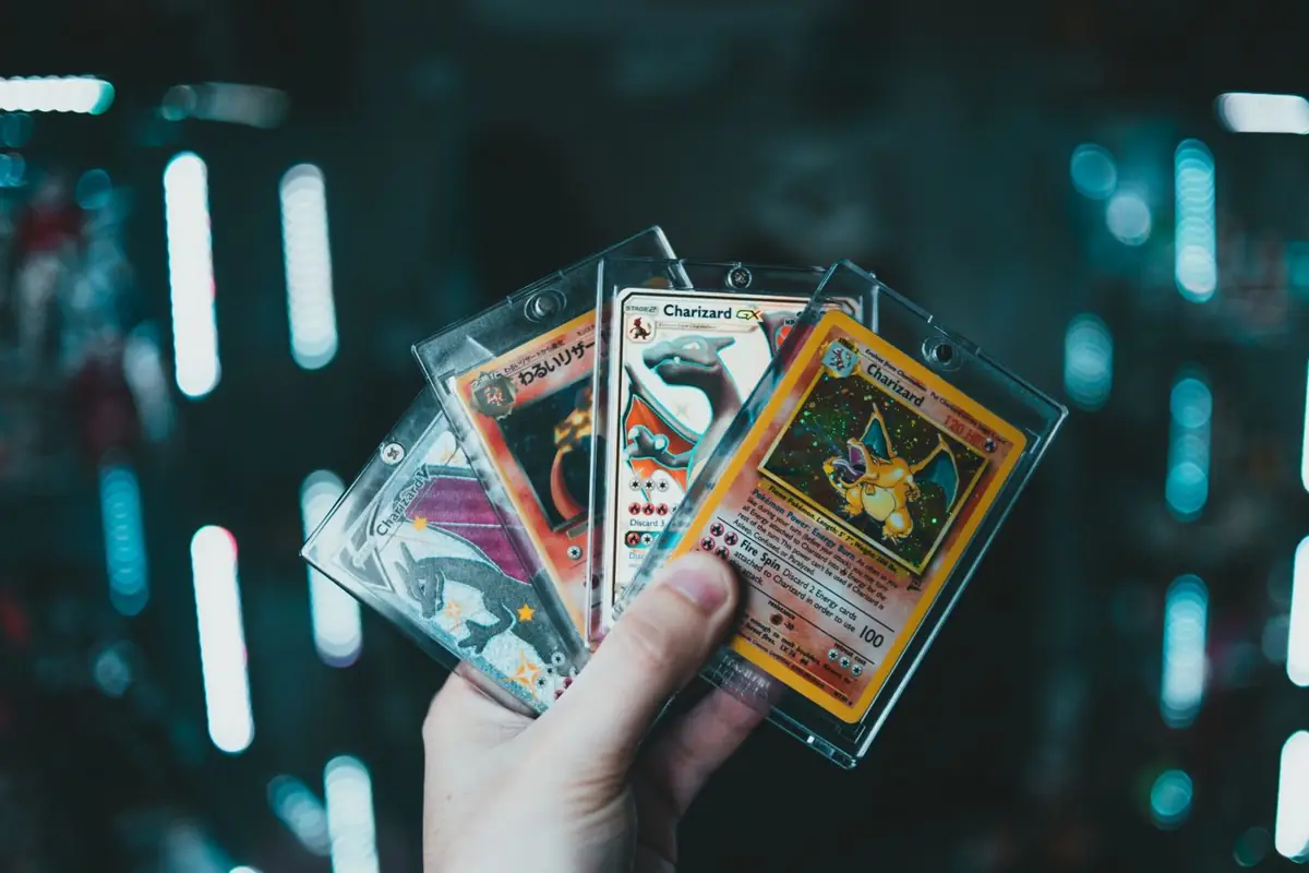 A hand holding Pokémon cards in toploaders